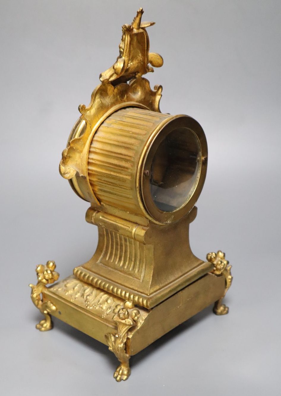 A 19th century French gilt metal mantel timepiece, with ceramic dial, pendulum and key, 31cm